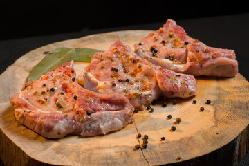 Raw pork ribs with spices, salt and rosemary on dark wooden background