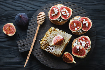 Bruschettas with figs, cheese and honey on a dark wooden surface