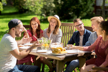 happy friends having dinner at summer garden party