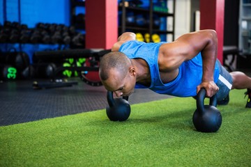 Man doing push-ups with kettlebells