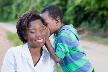 child talking secretly to his mother's ear in campaign