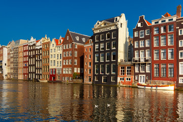 Naklejka premium Beautiful typical Dutch dancing houses at the Amsterdam canal Damrak in sunny day, Holland, Netherlands.