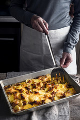 Cutting tartiflette in the baking tray  on the wooden table