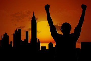 silhouette of cheering person with city and sunset background