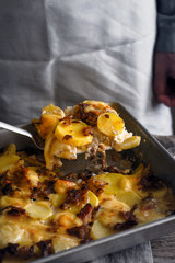 Tartiflette in the backing tray with slice on the spatula