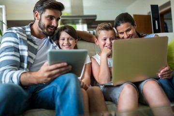 Fototapeta premium Happy family using laptop and digital tablet in the living room 