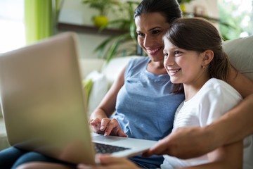 Mother and daughter using laptop and tablet