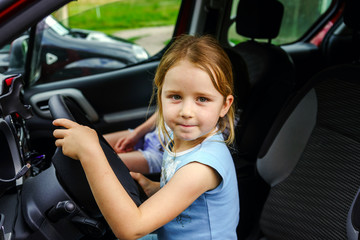 Fototapeta na wymiar Cute little girl sitting on driver place in a car