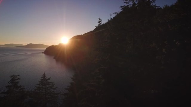 Aerial of Sun Beams Flashing Between Shadows of Trees to Reveal Sunset on Ocean Islands