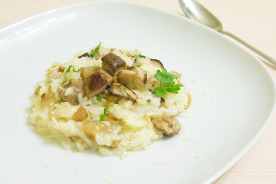 Risotto with mushrooms, parmesan cheese and parsley on a wooden background