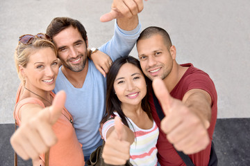 Portrait of four young adults showing thumbs up - Powered by Adobe