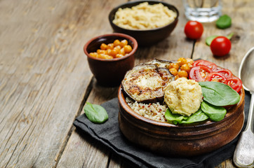 Mediterranean quinoa hummus bowl with eggplants, tomatoes and sp