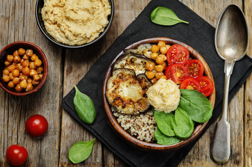 Mediterranean quinoa hummus bowl with eggplants, tomatoes and sp