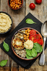 Mediterranean quinoa hummus bowl with eggplants, tomatoes and sp