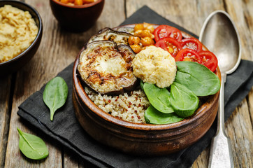 Mediterranean quinoa hummus bowl with eggplants, tomatoes and sp