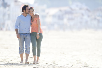 Middle-aged couple walking on the beach - obrazy, fototapety, plakaty