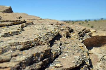 Close up of lichen covered layered stone overlooking desert landscape 