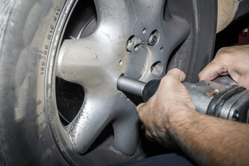 Mecánico reparando la trasmisión y los frenos de un coche en el taller. Reparación de vehículos. Revisión y mantenimiento. Cambio de neumáticos. 