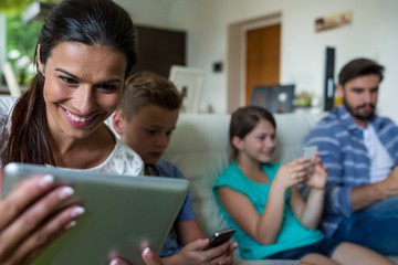 Fototapeta na wymiar Family using laptop and mobile phone in living room
