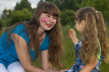 little daughter  draws crayons on face mom