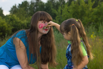 little daughter  draws crayons on face mom