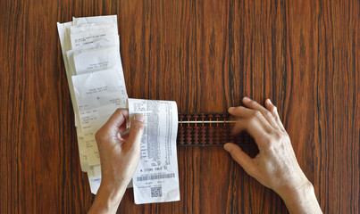 Fototapeta na wymiar Checking Receipts With Abacus on Wood Table