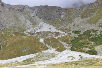 Two small creeks are flowing down the Grubenkopf mountain into the Lake Rifflsee, 2200 meters above sea level. In the Pitztal, Tyrolian Alps, Austria, Europe.  