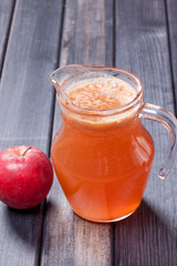 fresh apple juice and red apples in the pitcher on table