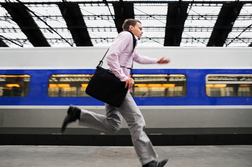 Businessman running through train station to catch last commuter light rail train
