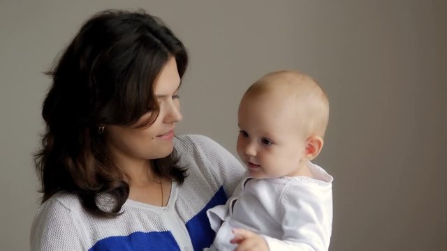 Young Happy Mother Holding her Newborn Child. Family at home. Beautiful smiling Mom and Happy Baby Together.