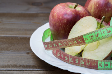 Green and red apples wrapped with measuring tape