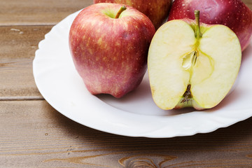 Naklejka na ściany i meble Four fresh red apples in white plate on wooden background