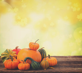 orange raw pumpkins with fall leaves on wooden table with autumn garden background, retro toned
