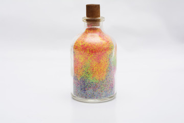 Decorative glass bottle with colorful sand isolated on white
