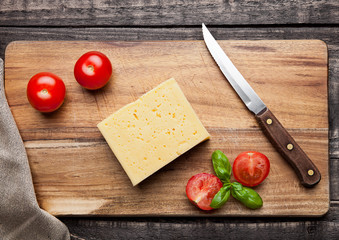Cheese with tomatoes and basil on wood with knife