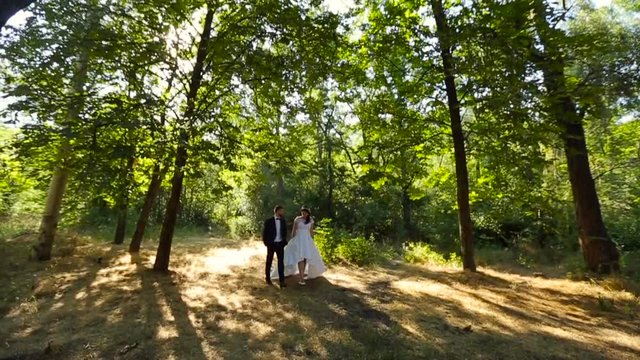 Bride and groom walk in beautiful park