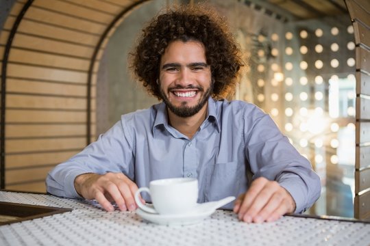 Man sitting on bar counter with cup of tea