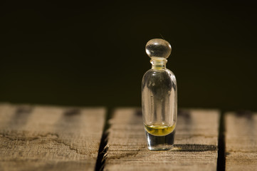 Closeup small glass bottle for magicians with tiny amount of remedy inside, standing on wooden...