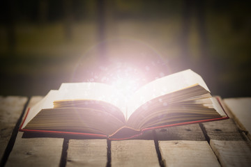 Thick book lying open on wooden surface, glowing animated star dust coming out, beautiful night light setting, magic concept shoot