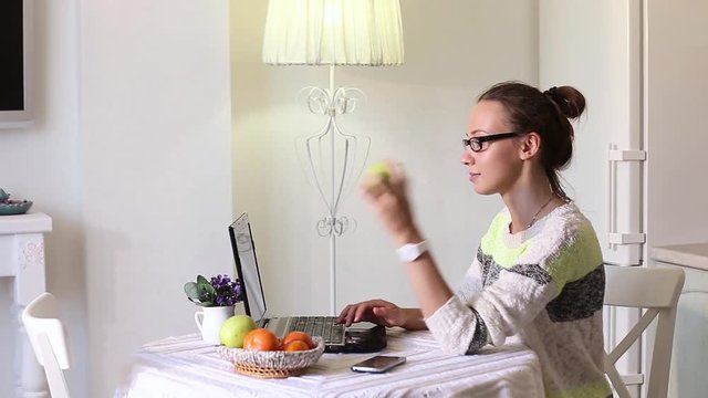Woman eating fruit while working on computer in office