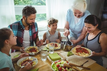 Elderly woman  serving meal to her family