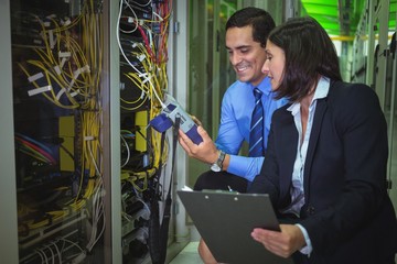 Obraz na płótnie Canvas Technicians using digital cable analyzer while analyzing server