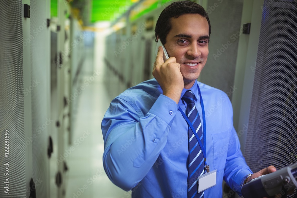 Poster Technicians talking on mobile phone while analyzing server