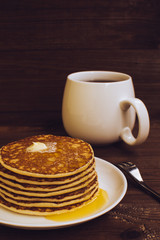 Stack of tasty pancakes with butter and honey for breakfast