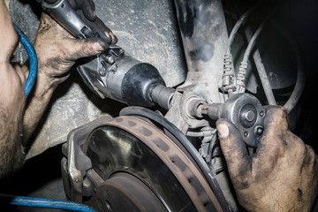 Mecánico reparando la trasmisión y los frenos de un coche en el taller. Reparación de vehículos. Revisión y mantenimiento. Cambio de neumáticos. 