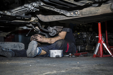 Mecánico reparando la trasmisión y los frenos de un coche en el taller. Reparación de...