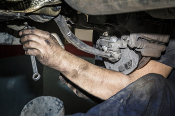 Mecánico reparando la trasmisión y los frenos de un coche en el taller. Reparación de...