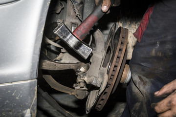 Mecánico reparando la trasmisión y los frenos de un coche en el taller. Reparación de vehículos. Revisión y mantenimiento. Cambio de neumáticos. 