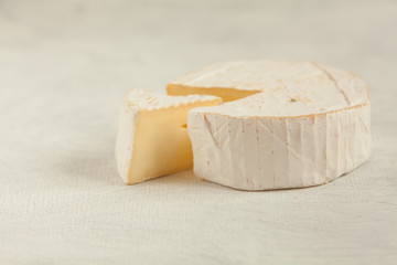 Fresh brie cheese with white mold on a white background