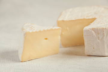 Fresh brie cheese with white mold on a white background